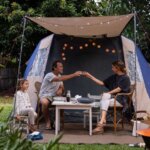 Family enjoying a backyard camping experience with a tent, fire pit, and outdoor seating.
